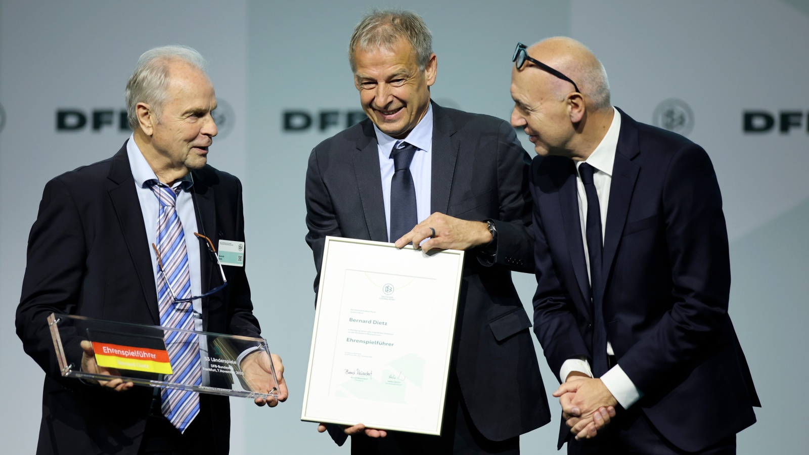 Bernard "Ennatz" Dietz (links) ist neuer DFB-Ehrenspielführer. Es gratulieren DFB-Präsident Bernd Neuendorf (rechts) und Ex-Nationalspieler und -Trainer Jürgen Klinsmann (Mitte).