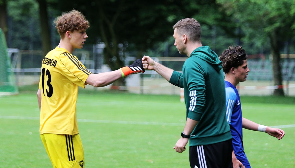 [{"clang_id":1,"value":"Fußball: Spieler mit Trikotnummer 13 gibt einem Trainer/Betreuer die Hand. Im Hintergrund weitere Spieler auf dem Rasen."}]
