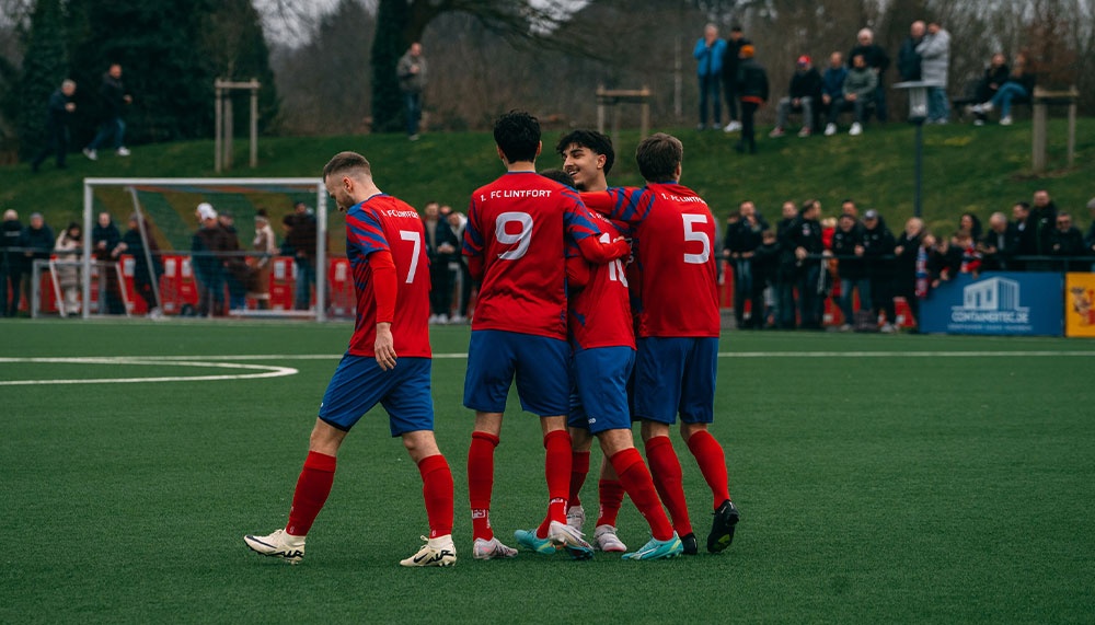 [{"clang_id":1,"value":"Fußballspieler in Rot-Blau feiern auf grünem Rasen. Im Hintergrund Zuschauer und ein Zaun."}]