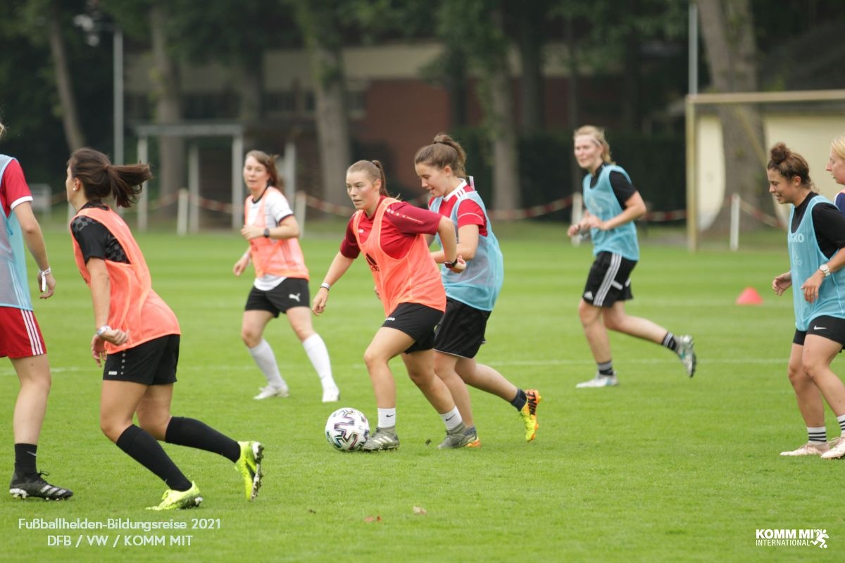[{"clang_id":1,"value":"Frauenfußballtraining auf grünem Rasenfeld. Mehrere Spielerinnen in Trainingskleidung dribbeln oder laufen mit Ball. Bäume im Hintergrund."}]