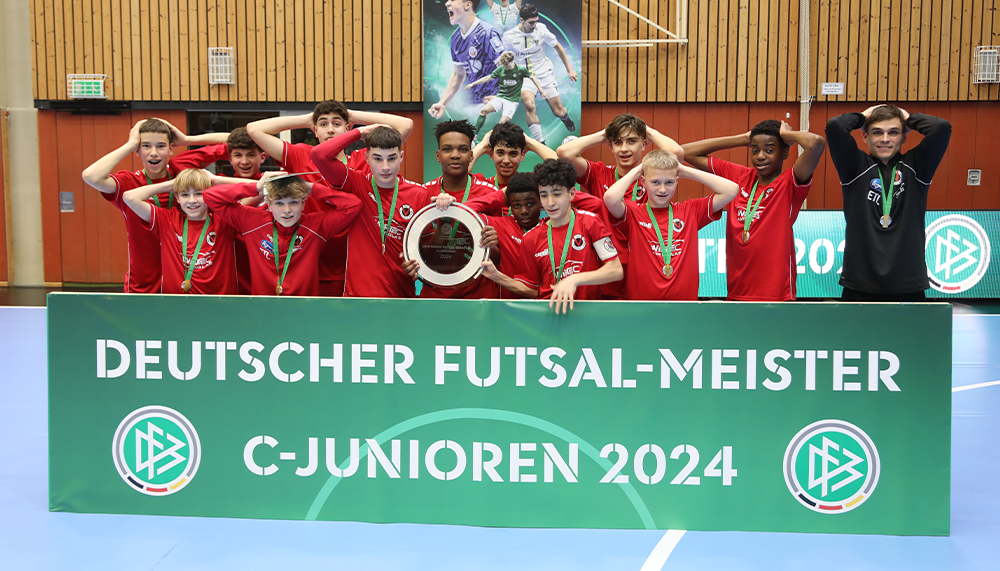 [{"clang_id":1,"value":"Futsal-Mannschaft C-Junioren 2024 mit Pokal vor grünem Banner mit Aufschrift \"Deutscher Futsal-Meister\". Gruppe von Jugendlichen in roten Trikots."}]