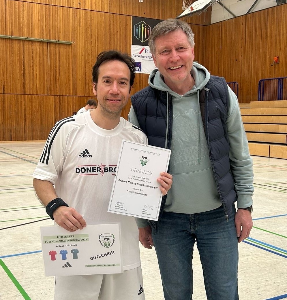[{"clang_id":1,"value":"Zwei Männer posieren lächelnd mit einer Urkunde und einem Gutschein in einer Sporthalle. Der Mann links trägt ein Futsal-Trikot, der andere eine Trainingsjacke."}]