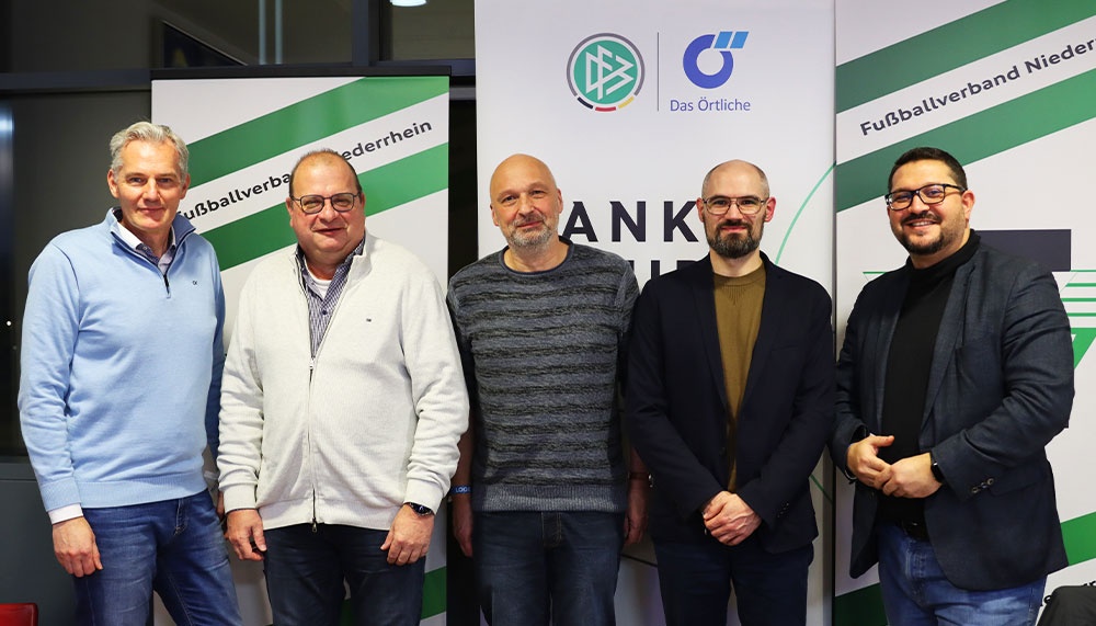 [{"clang_id":1,"value":"Fünf Männer stehen nebeneinander vor einem Banner mit Logos und Schriftzügen. Sie tragen Freizeit- oder Geschäftskleidung."}]