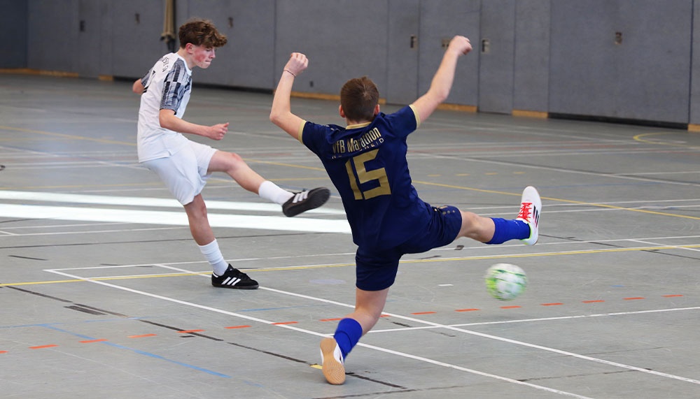[{"clang_id":1,"value":"Zwei Futsalspieler in blauer und weißer Sportbekleidung im Hallensportfeld. Ein Spieler schießt den Ball, der andere verteidigt."}]