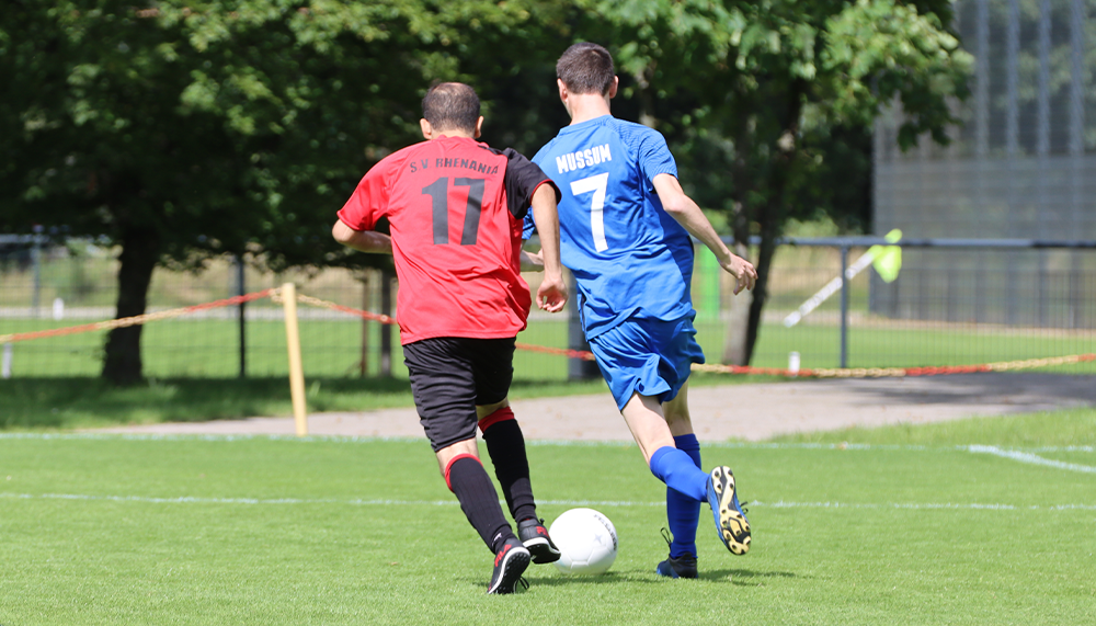 [{"clang_id":1,"value":"Zwei Fußballspieler auf grünem Rasen. Links trägt ein Spieler rotes Trikot mit Nummer 17, rechts ein blaues Trikot mit Nummer 7 und \"HUSSIM\". Sie spielen den Ball."}]