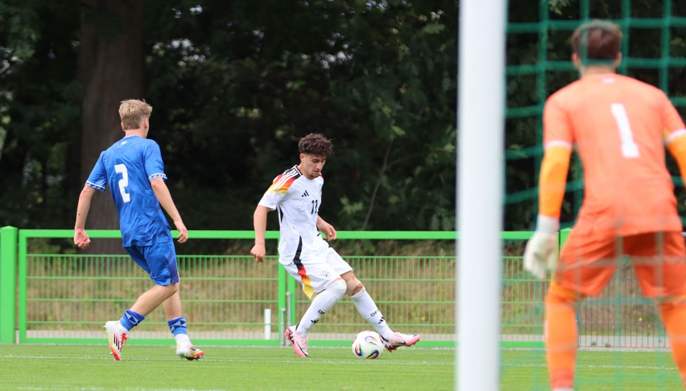 [{"clang_id":1,"value":"Fußballspiel: Spieler mit Ball im Angriff, blauer Gegenspieler und Torwart im Hintergrund. Grünfläche, Zaun."}]