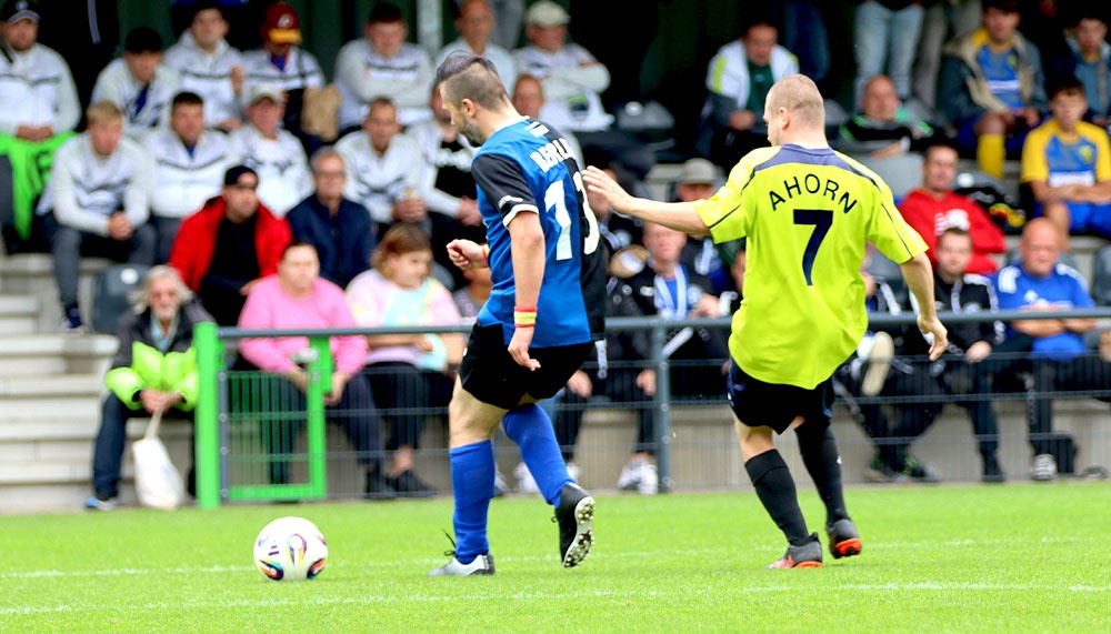[{"clang_id":1,"value":"Zwei Fußballspieler kämpfen um den Ball auf grünem Rasen. Im Hintergrund Zuschauerreihen. Spieler tragen Trikots mit Nummern 7 und 11."}]