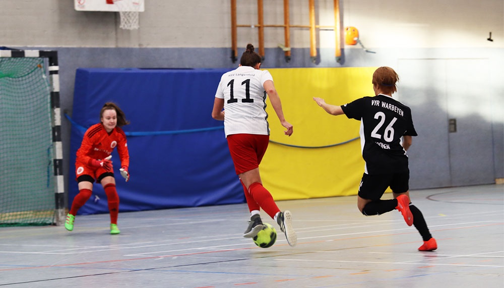 [{"clang_id":1,"value":"Handballspiel in Sporthalle: Zwei Spielerinnen in Aktion, eine in Rot, eine in Weiß-Schwarz. Im Hintergrund blauer und gelber Hallenboden."}]