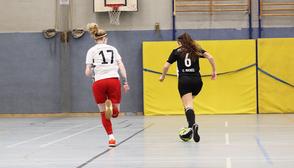 [{"clang_id":1,"value":"Zwei Handballspielerinnen in einem Hallensportraum. Eine trägt Weiß-Rot, die andere Schwarz mit der Nummer 6 und kickt einen Ball. Im Hintergrund eine Wand und ein Basketballkorb."}]