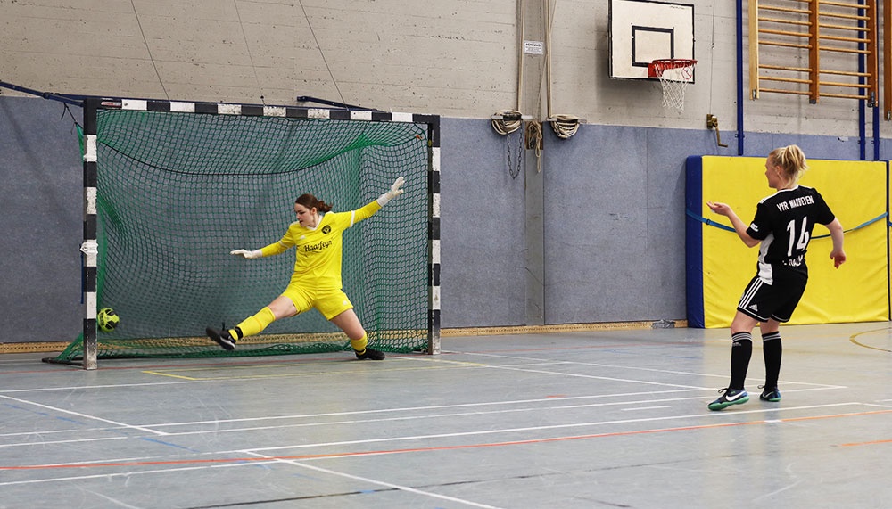 [{"clang_id":1,"value":"Futsalspiel in Sporthalle: Torwart in gelbabwehrend Schuss, Spielerin mit Ball, dunkles Trikot, Nummer 14."}]