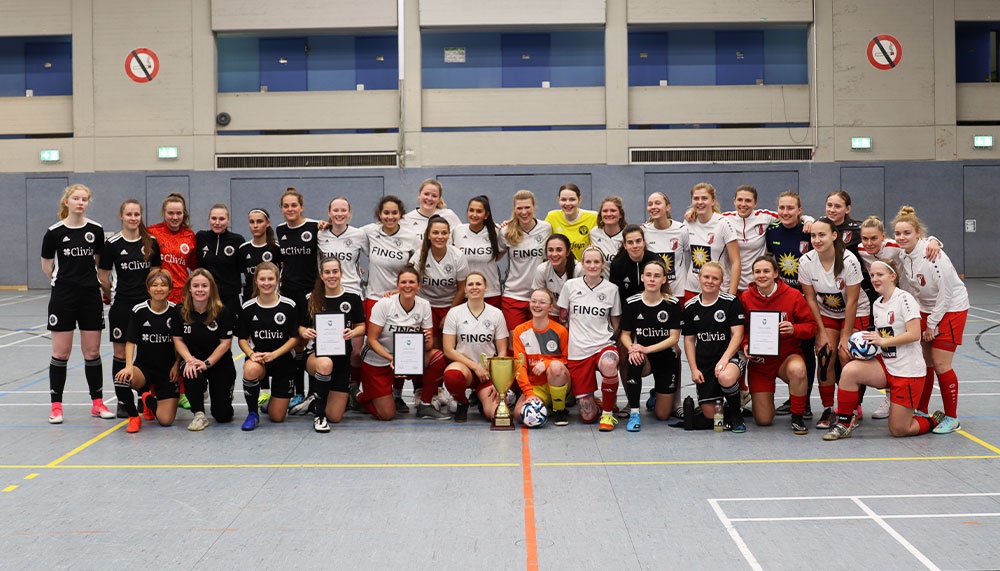 [{"clang_id":1,"value":"Fußballmannschaft, kniend und stehend, mit Trikots und Urkunden in einer Sporthalle. Frauenporträts."}]