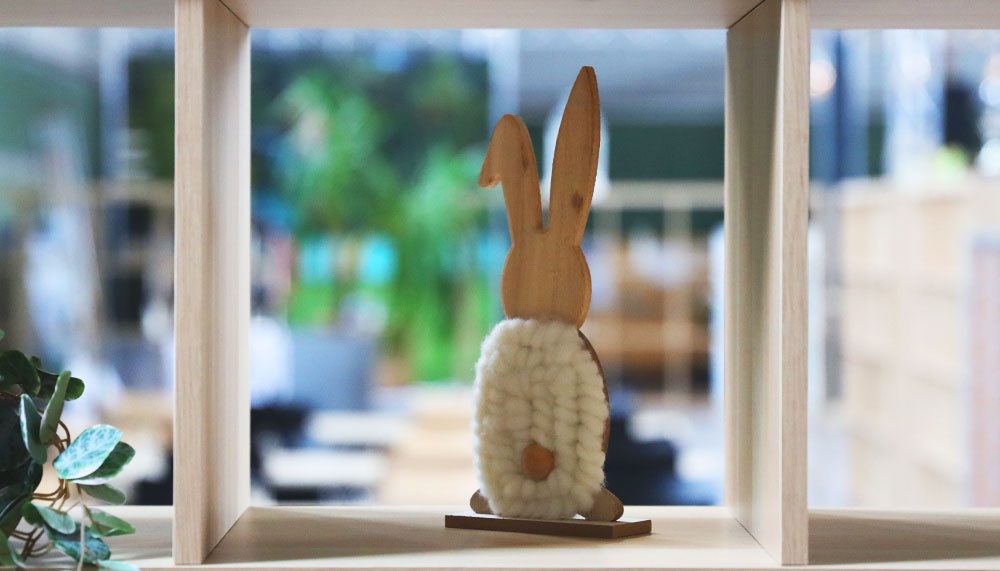 [{"clang_id":1,"value":"Holzregal mit Dekohase. Der Hase hat einen Holzkopf und einen Körper aus weißen Pompons. Im Hintergrund verschwommene Innenraumansicht."}]