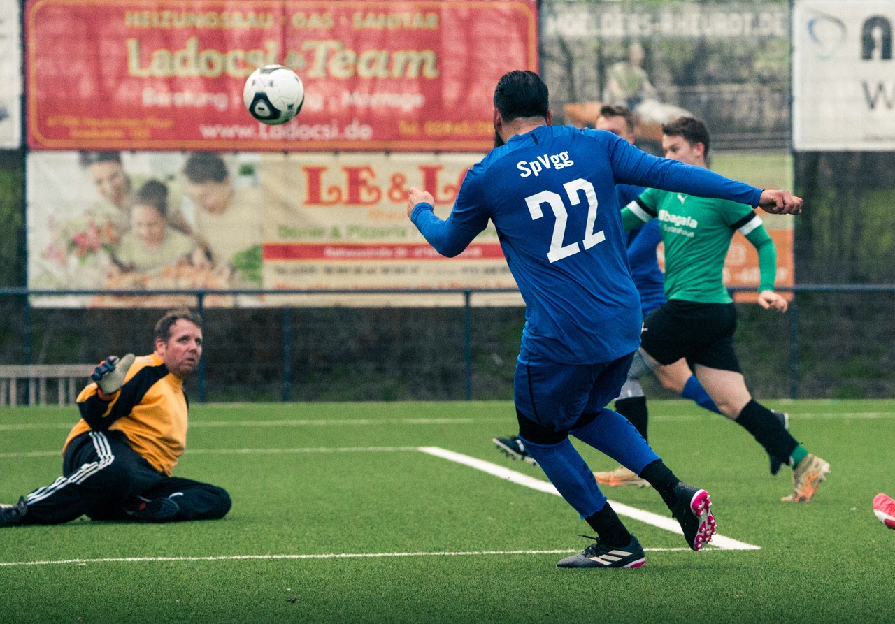 [{"clang_id":1,"value":"Fußballspiel: Spieler mit Nummer 22 dribbelt den Ball, während der Torwart in die Hocke geht. Im Hintergrund weitere Spieler und Werbebanner."}]