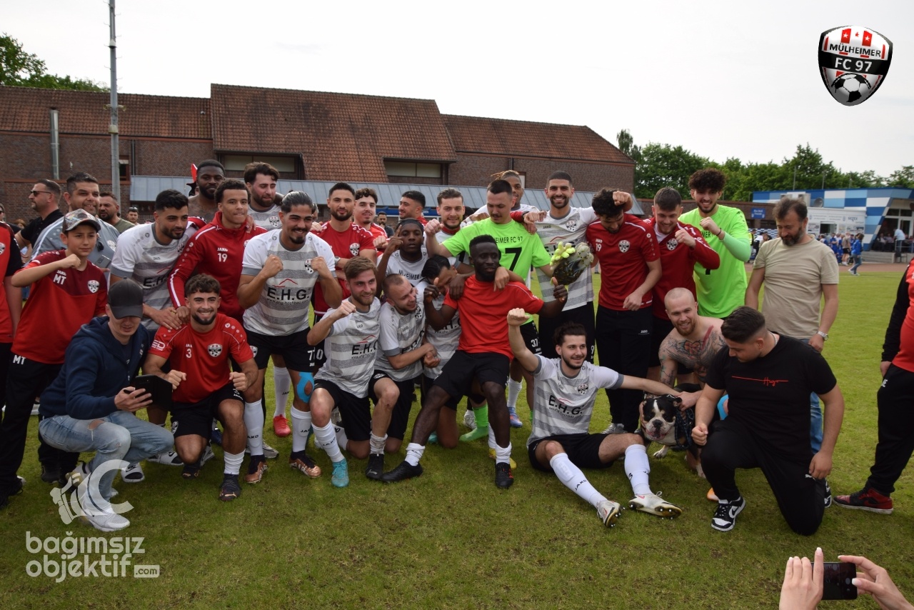[{"clang_id":1,"value":"Fußballmannschaft in Jubelpose auf dem Rasen. Spieler in rot-weißen und grau-schwarzen Trikots umarmen sich und halten Blumen. Im Hintergrund Gebäude und Zuschauer."}]