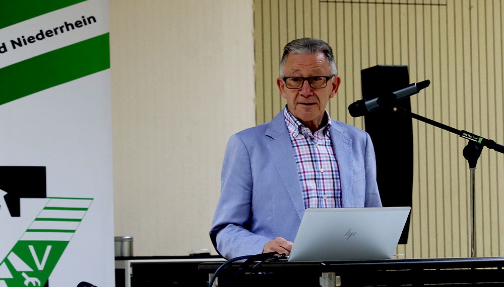 [{"clang_id":1,"value":"Mann mit Brille am Laptop vor Wand mit grünem Banner und Schriftzug \"Niederrhein\". Mikrofonsystem rechts."}]