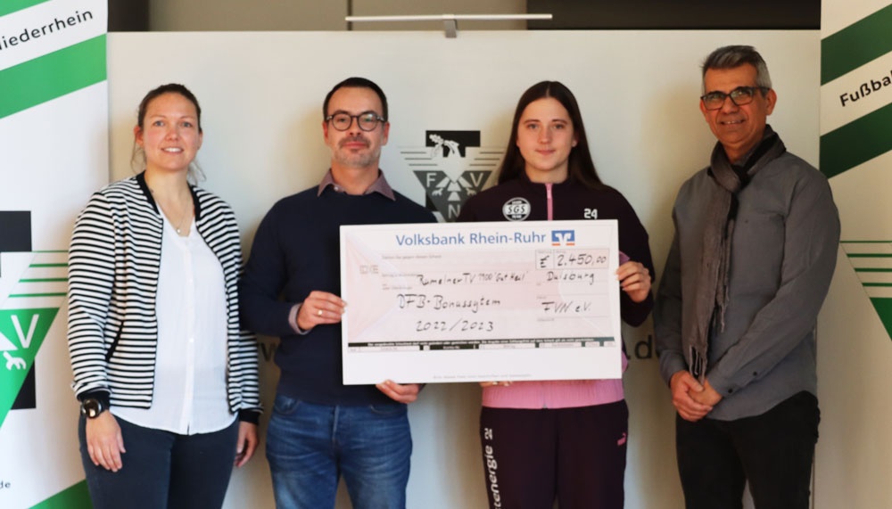 [{"clang_id":1,"value":"Vier Personen präsentieren einen Scheck der Volksbank Rhein-Ruhr an eine junge Sportlerin. Hintergrund: Vereinslogo und Werbebanner."}]