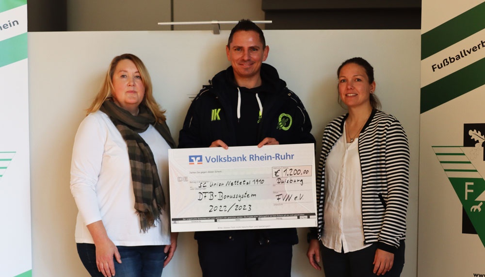 [{"clang_id":1,"value":"Drei Personen vor einem Banner mit Logo und Scheck. Mittlere Person hält einen Scheck über 1.200,00 Euro von Volksbank Rhein-Ruhr für SG Union Nettesheim 1910."}]