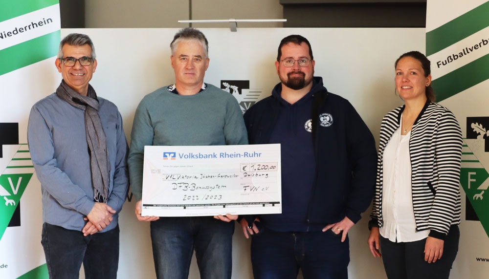 [{"clang_id":1,"value":"Fünf Personen posieren mit einem Scheck. Der Scheck ist von Volksbank Rhein-Ruhr über 7.200 Euro an VfL Victoria Jugendfußball Duisburg. Im Hintergrund grüne Wände mit Logos."}]