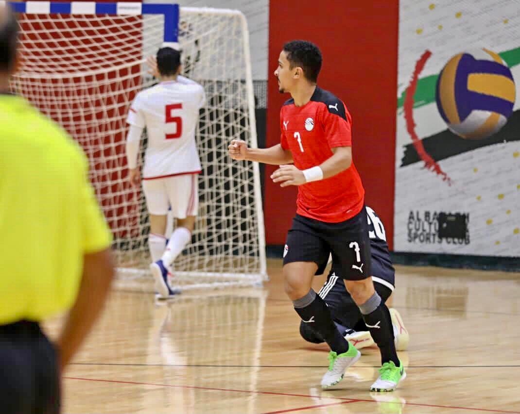 [{"clang_id":1,"value":"Zwei Futsalspieler in roten Trikots und schwarzer Hose auf Indoor-Spielfeld. Im Hintergrund ein Tor und eine Werbetafel."}]