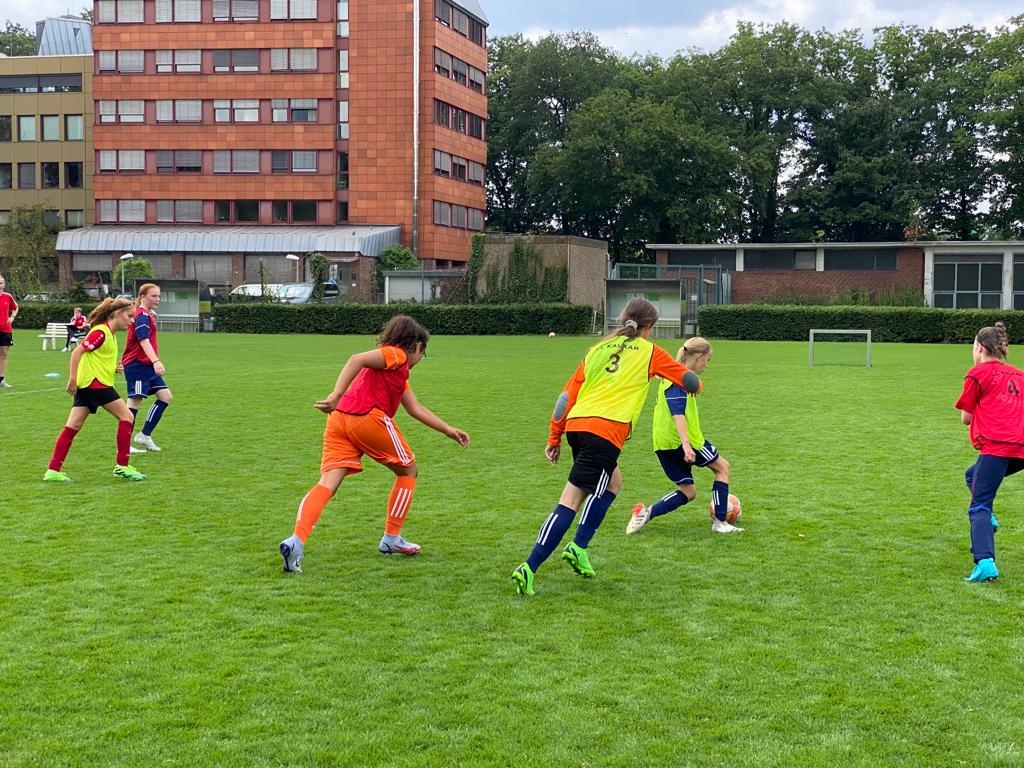 [{"clang_id":1,"value":"Fußballspiel mit mehreren Jugendlichen auf einem Rasenplatz. Im Hintergrund ein mehrstöckiges Wohngebäude und Bäume."}]