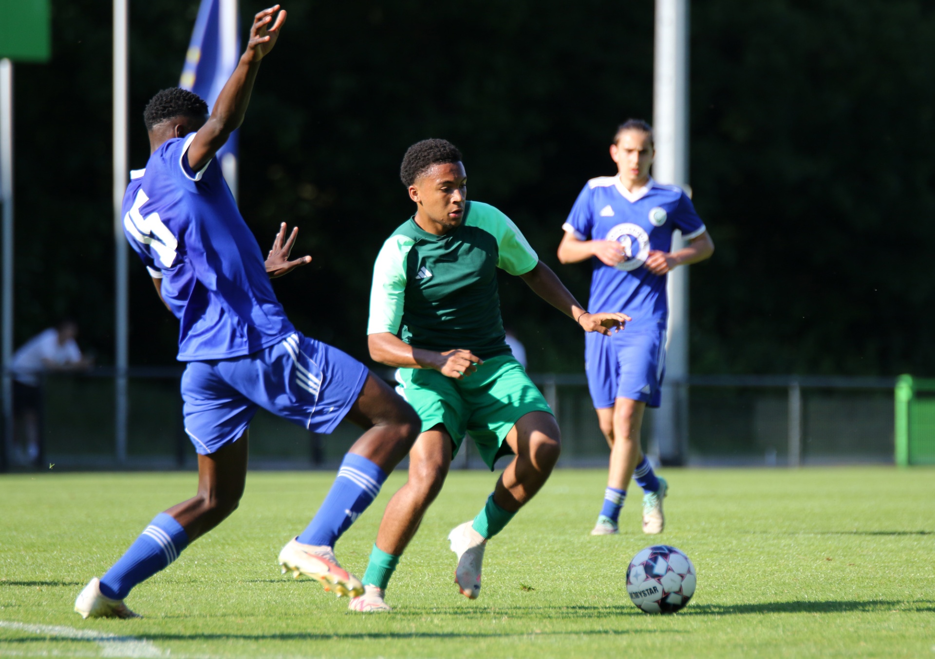 [{"clang_id":1,"value":"Fußballspiel. Ein Spieler in grün dribbelt den Ball, wird von einem Spieler in blau gefoult, während ein weiterer blauer Spieler im Hintergrund steht."}]