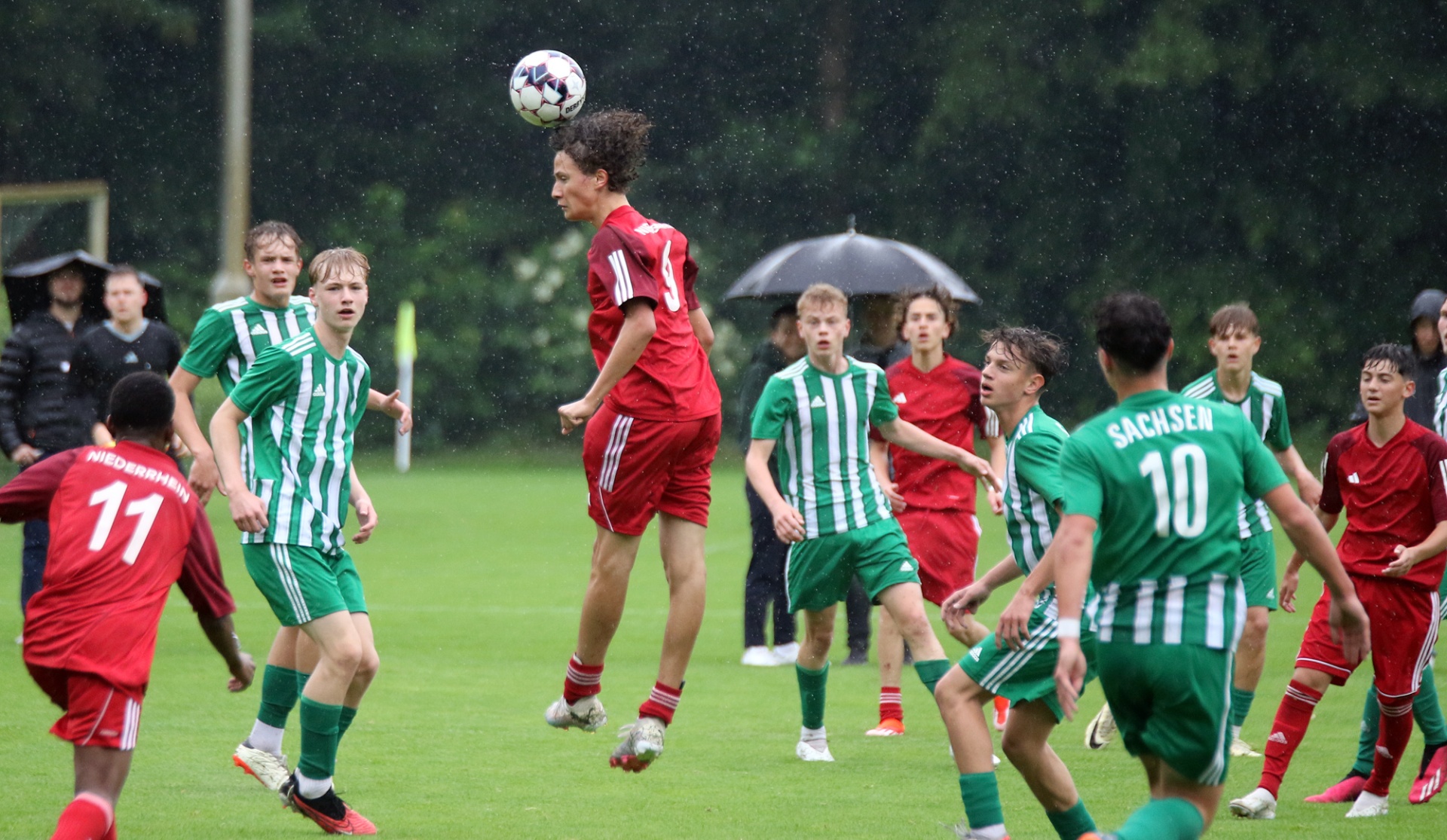 [{"clang_id":1,"value":"Fußballspiel: Spieler in roten und grün-weißen Trikots kämpfen um den Ball. Ein Spieler köpft den Ball hoch in die Luft. Im Hintergrund Zuschauer."}]