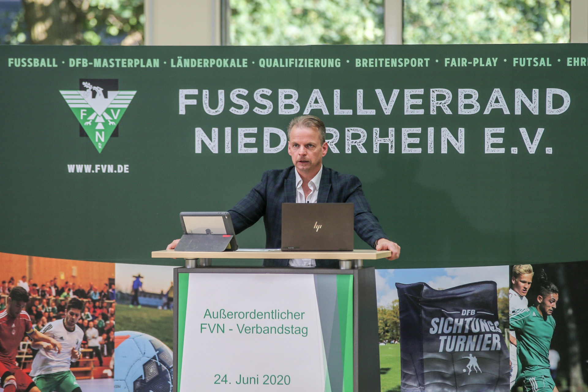 [{"clang_id":1,"value":"Mann am Rednerpult mit Logo \"FUSSBALLVERBAND NIEDERRHEIN E.V.\". Hintergrund: Fußballspieler auf Leinwand. Datum: 24. Juni 2020."}]