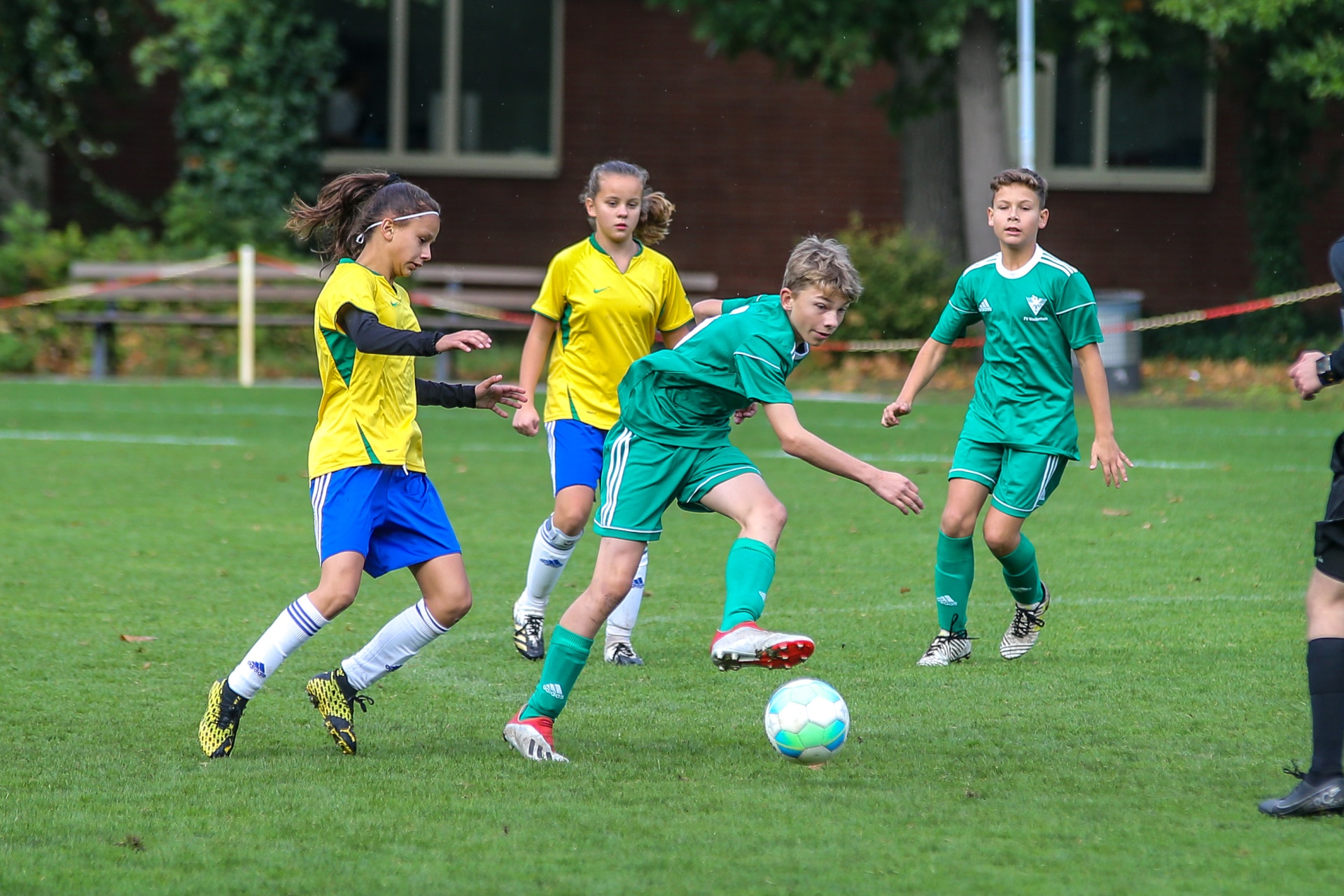[{"clang_id":1,"value":"Fußballspiel mit vier Kindern auf Rasenfeld. Zwei Mädchen in gelben Trikots, zwei Jungen in grünen Trikots. Alle in Bewegung, Ball im Fokus."}]