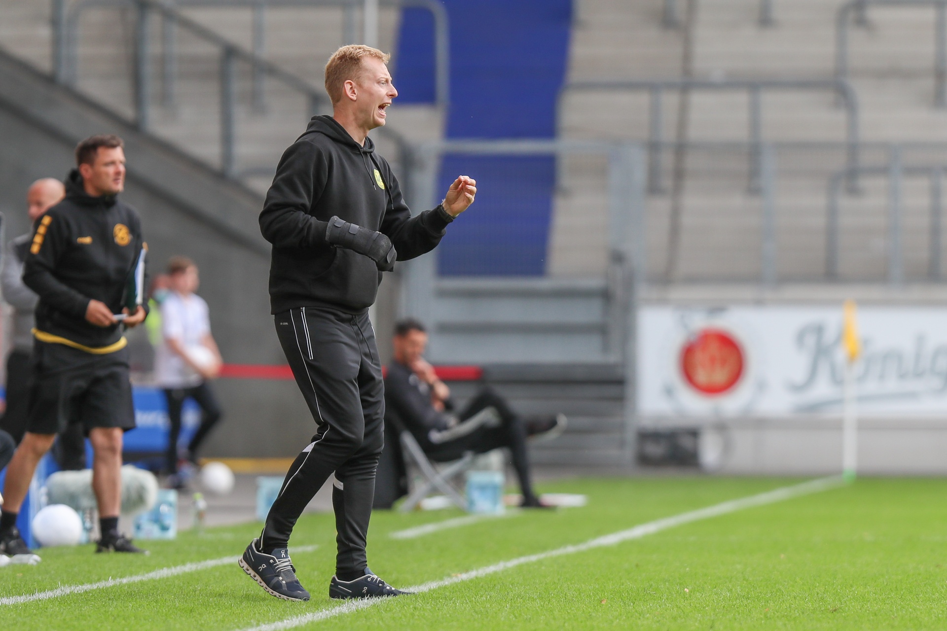 [{"clang_id":1,"value":"Fußballtrainer steht an der Seitenlinie und gestikuliert aufgeregt. Im Hintergrund Zuschauerreihen und Spielfeld."}]