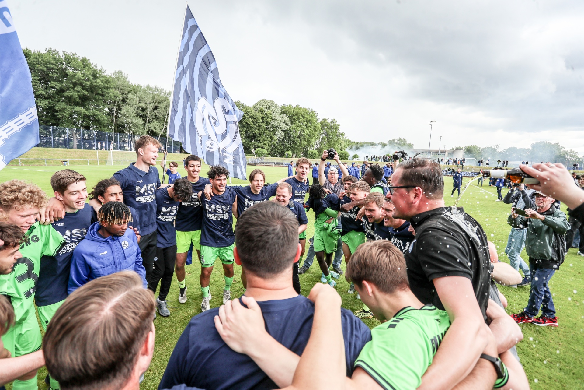 [{"clang_id":1,"value":"Fußballmannschaft feiert Sieg. Spieler umarmen sich, werden mit Konfetti beworfen. Im Hintergrund Banner und Zuschauer."}]