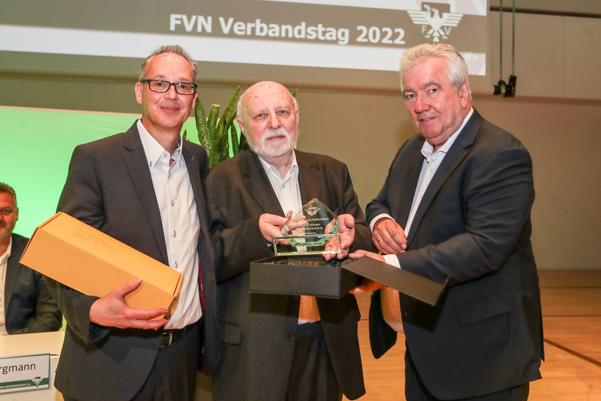 [{"clang_id":1,"value":"Drei Männer auf einer Bühne erhalten Auszeichnungen. Im Hintergrund eine Leinwand mit dem Schriftzug \"FVN Verbandstag 2022\"."}]