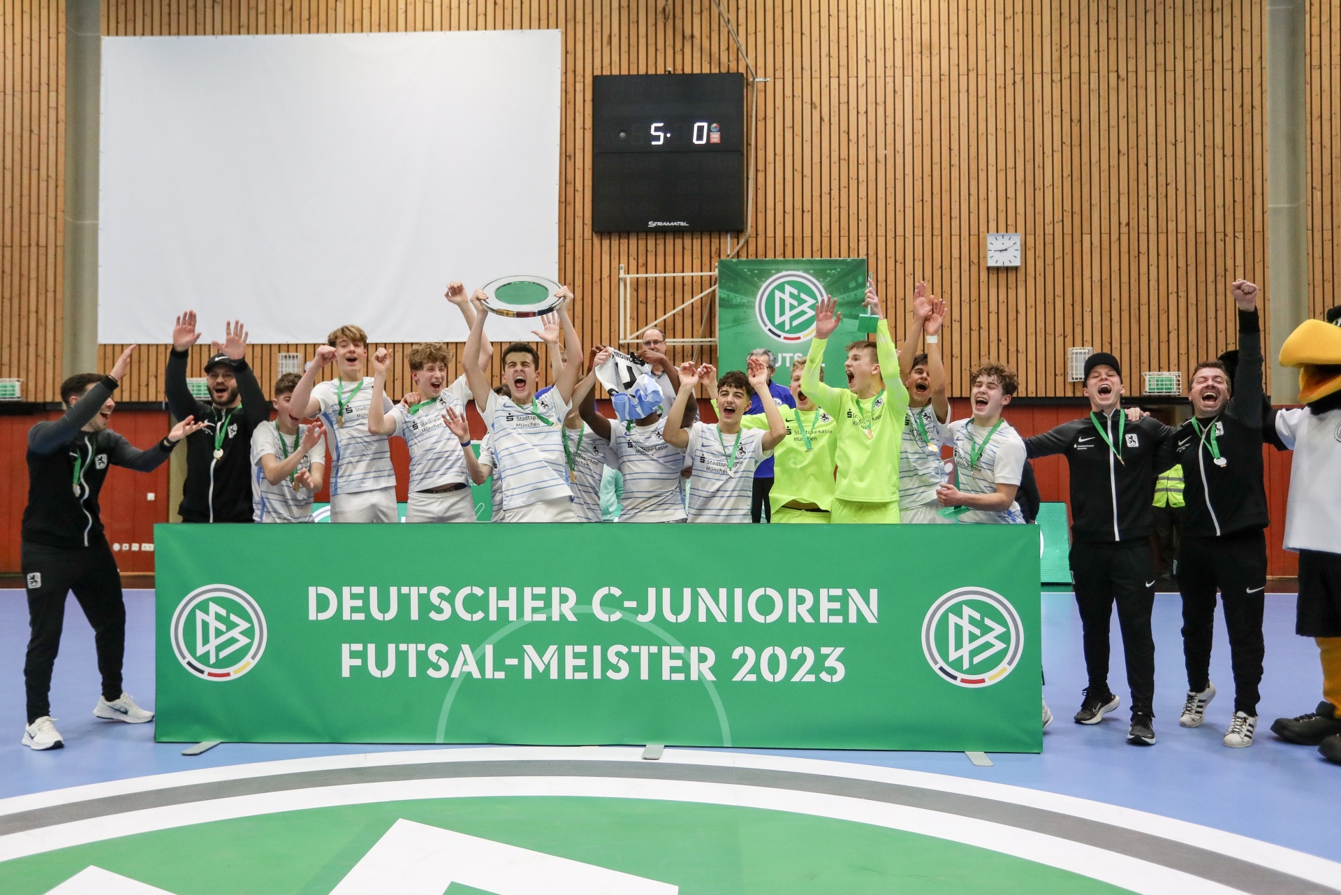 [{"clang_id":1,"value":"Futsal-Mannschaft feiert Sieg. Jugendliche Spieler mit Pokal und Banner \"Deutscher C-Junioren Futsal-Meister 2023\". Im Hintergrund Sporthalle."}]