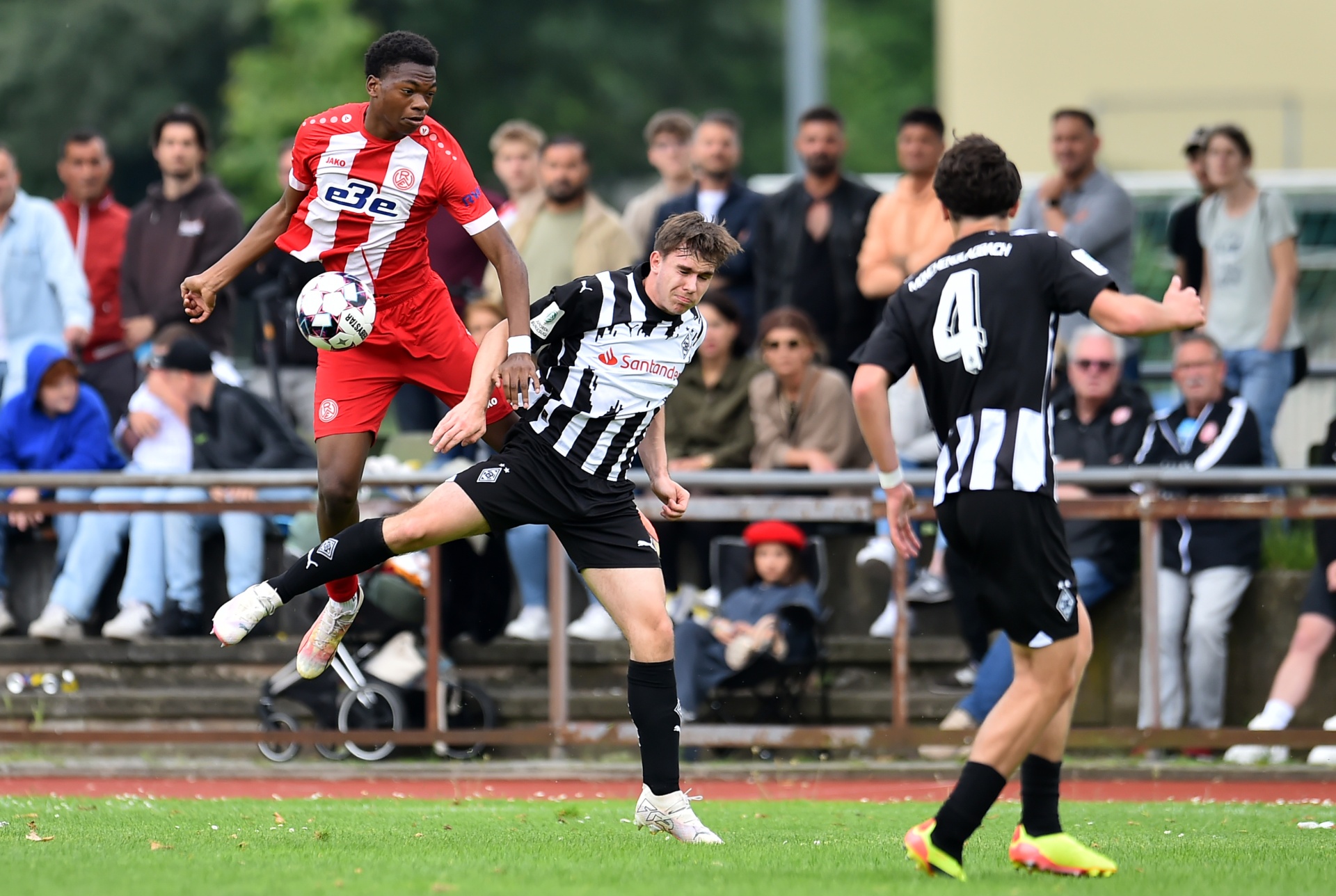 [{"clang_id":1,"value":"Fußballspiel: Zwei Spieler in Aktion, einer springt zum Ball, der andere versucht ihn zu blocken. Zuschauer im Hintergrund. Rasenplatz."}]