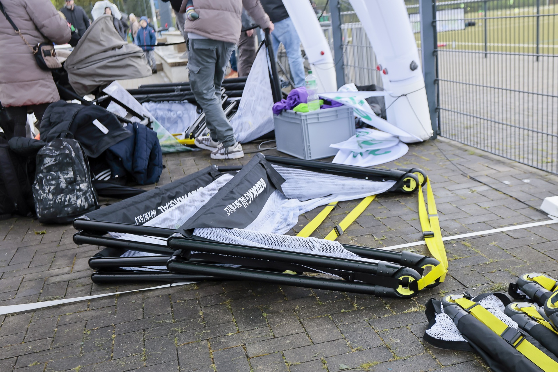 [{"clang_id":1,"value":"Zusammengeklapptes Fußballtor auf Pflastersteinboden. Im Hintergrund verschwommene Personen und weitere Sportausrüstung."}]