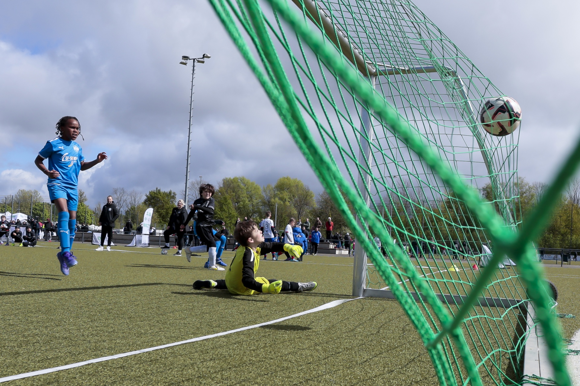 [{"clang_id":1,"value":"Fußballspiel: Spieler springt zum Schuss, Torwart liegt am Boden, Ball im Flug. Im Hintergrund weitere Spieler und Zuschauer."}]