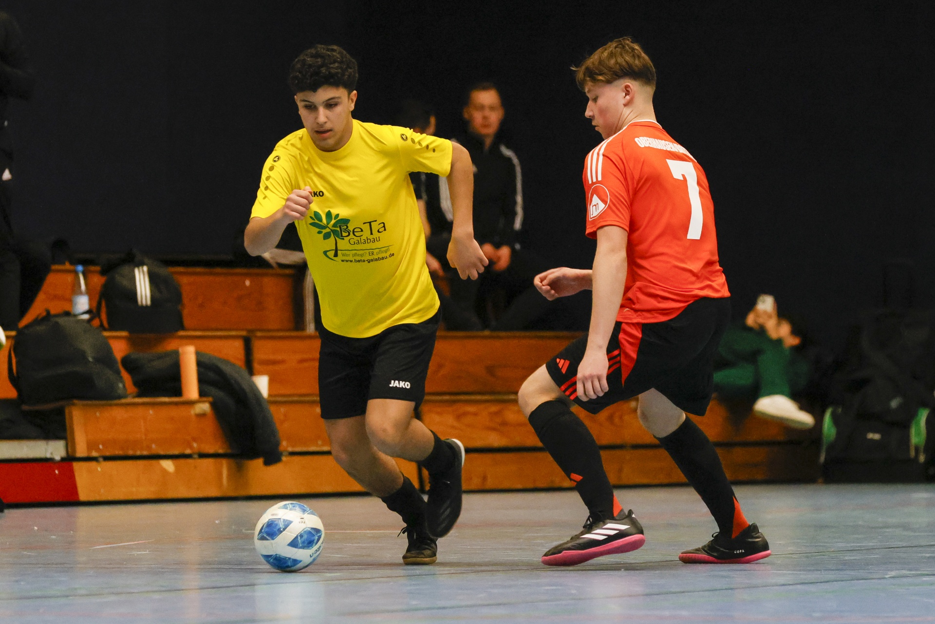 [{"clang_id":1,"value":"Zwei Futsalspieler in gelb und rot stehen auf Hallenboden. Ein Ball liegt zwischen ihnen. Im Hintergrund sind Zuschauer und eine Bank zu sehen."}]