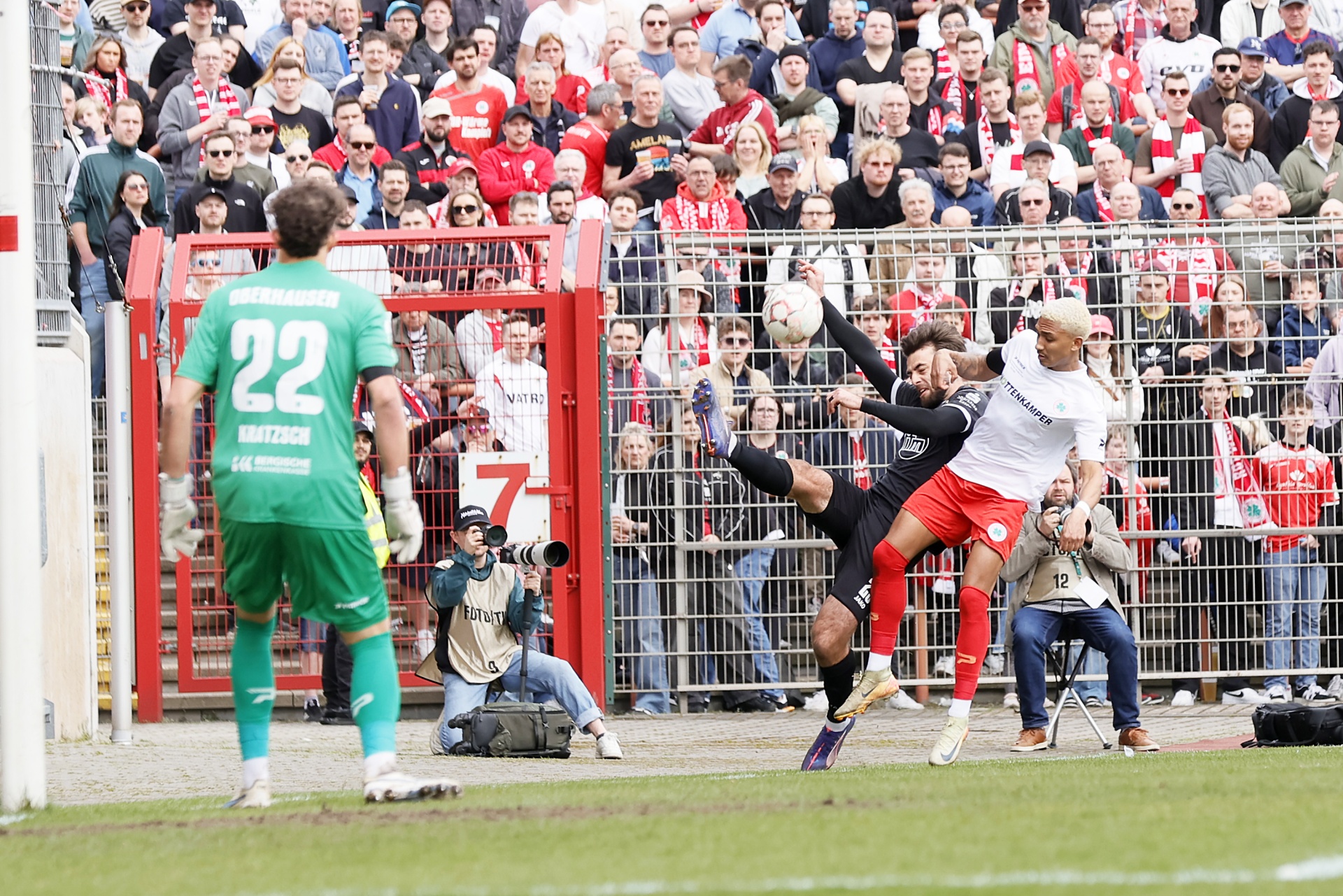 [{"clang_id":1,"value":"Fußballspiel: Spieler in weißen und grünen Trikots kämpfen um den Ball vor vollem Stadion. Im Hintergrund viele Zuschauer."}]