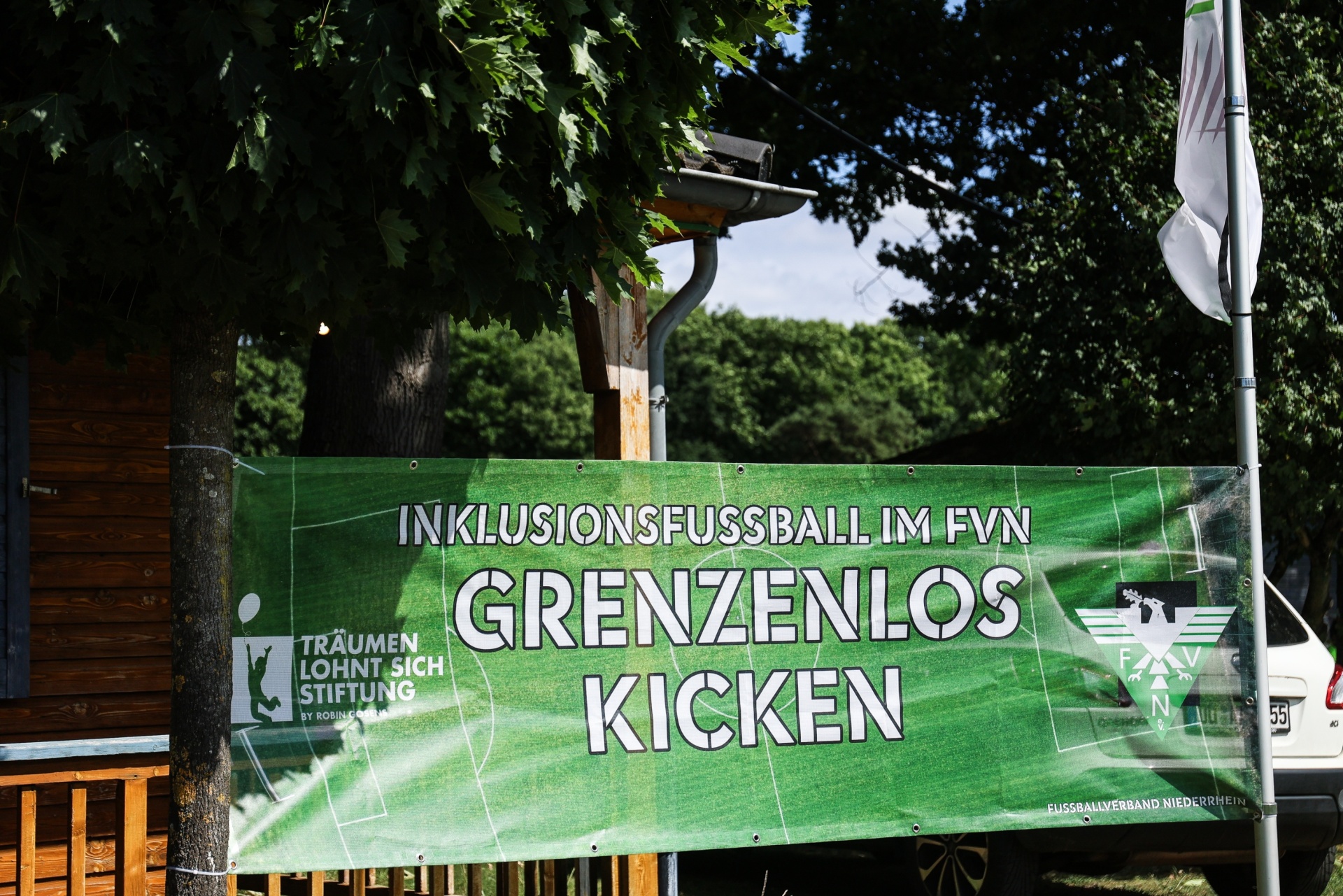 [{"clang_id":1,"value":"Grünes Banner mit weißer Schrift: \"Inklusionsfußball im FVN - Grenzenlos Kicken\". Im Hintergrund Bäume und ein Zaun."}]
