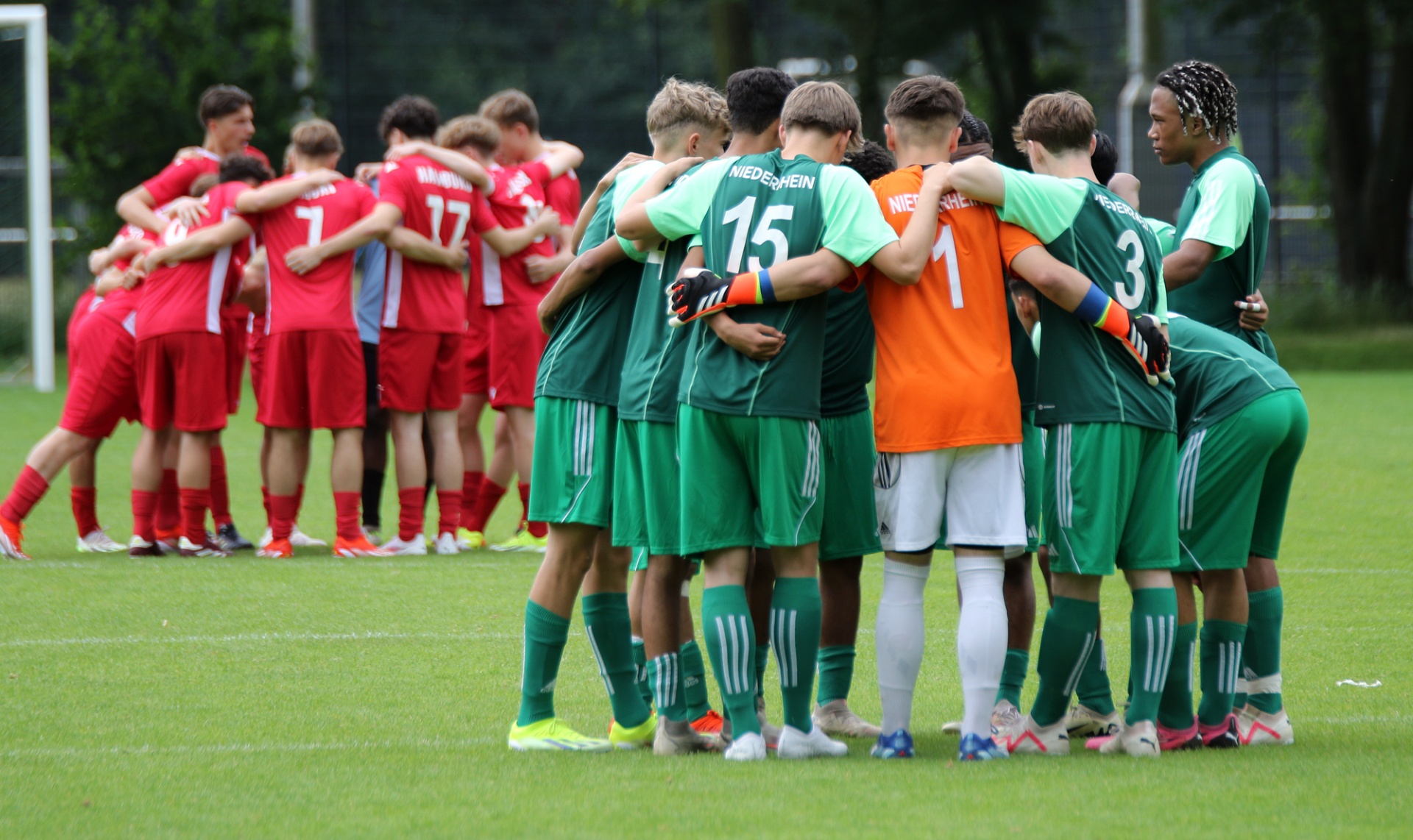 [{"clang_id":1,"value":"Zwei Fußballmannschaften stehen sich gegenüber und bilden einen Kreis. Eine Mannschaft trägt grüne Trikots, die andere rote. Sie scheinen sich vor dem Spiel zu motivieren."}]