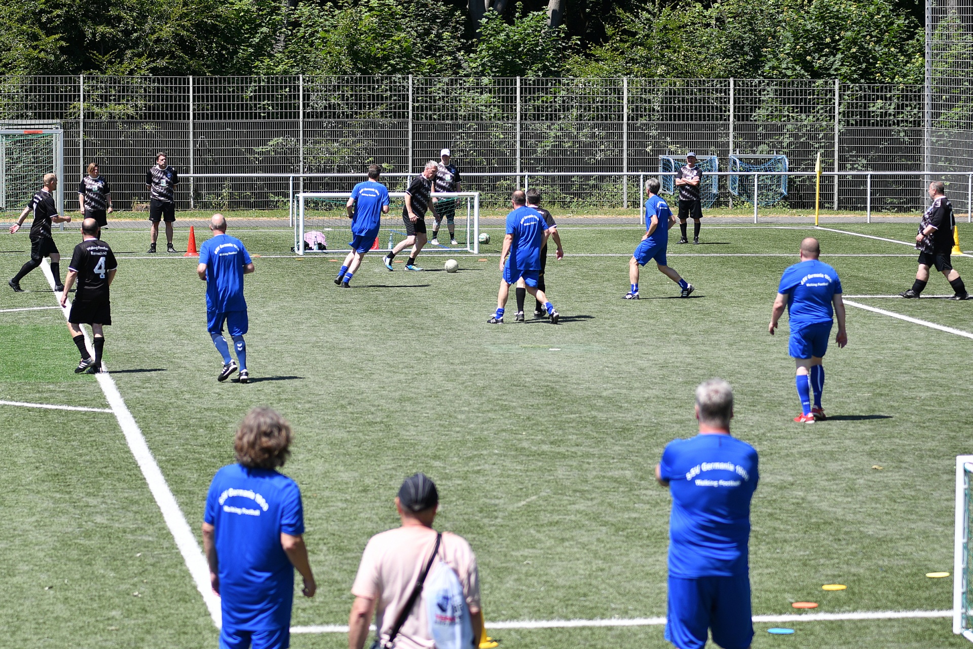 [{"clang_id":1,"value":"Fußballspiel auf grünem Kunstrasenfeld. Zwei Teams, eines in Blau, eines in Schwarz, kämpfen um den Ball. Zuschauer stehen am Spielfeldrand."}]