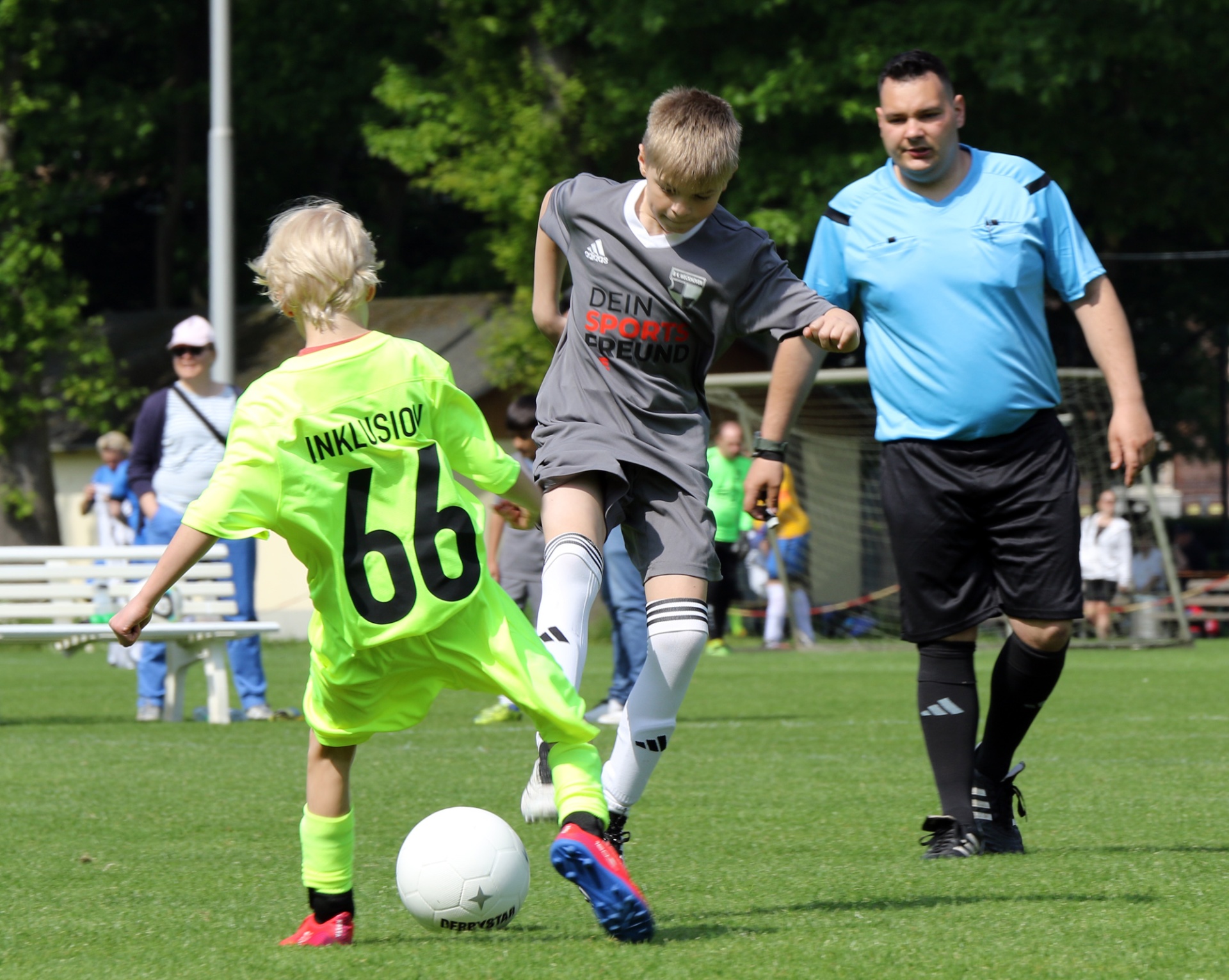 [{"clang_id":1,"value":"Fußballspiel. Junge mit Nummer 66 schießt auf Tor, Gegenspieler und Schiedsrichter im Hintergrund. Rasenplatz, sonniger Tag."}]