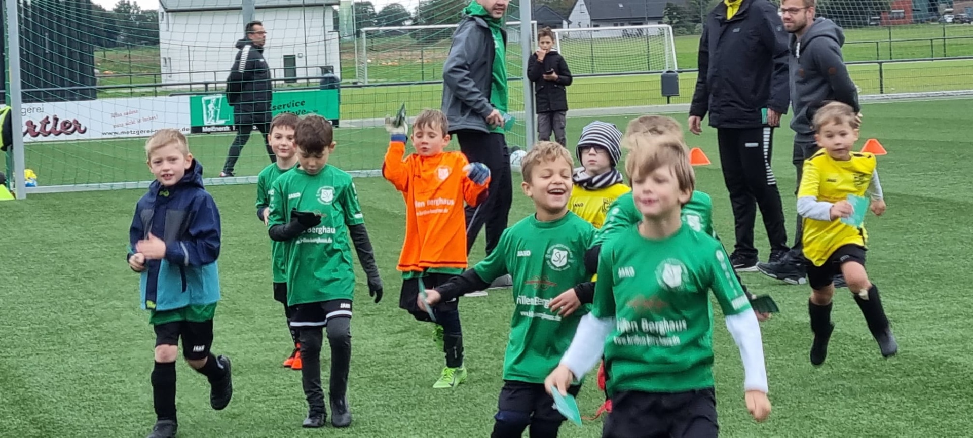 [{"clang_id":1,"value":"Fußballtraining mit Kindern. Eine Gruppe Jungen in Sportkleidung läuft auf einem grünen Kunstrasenplatz. Im Hintergrund Erwachsene und ein Stadion."}]