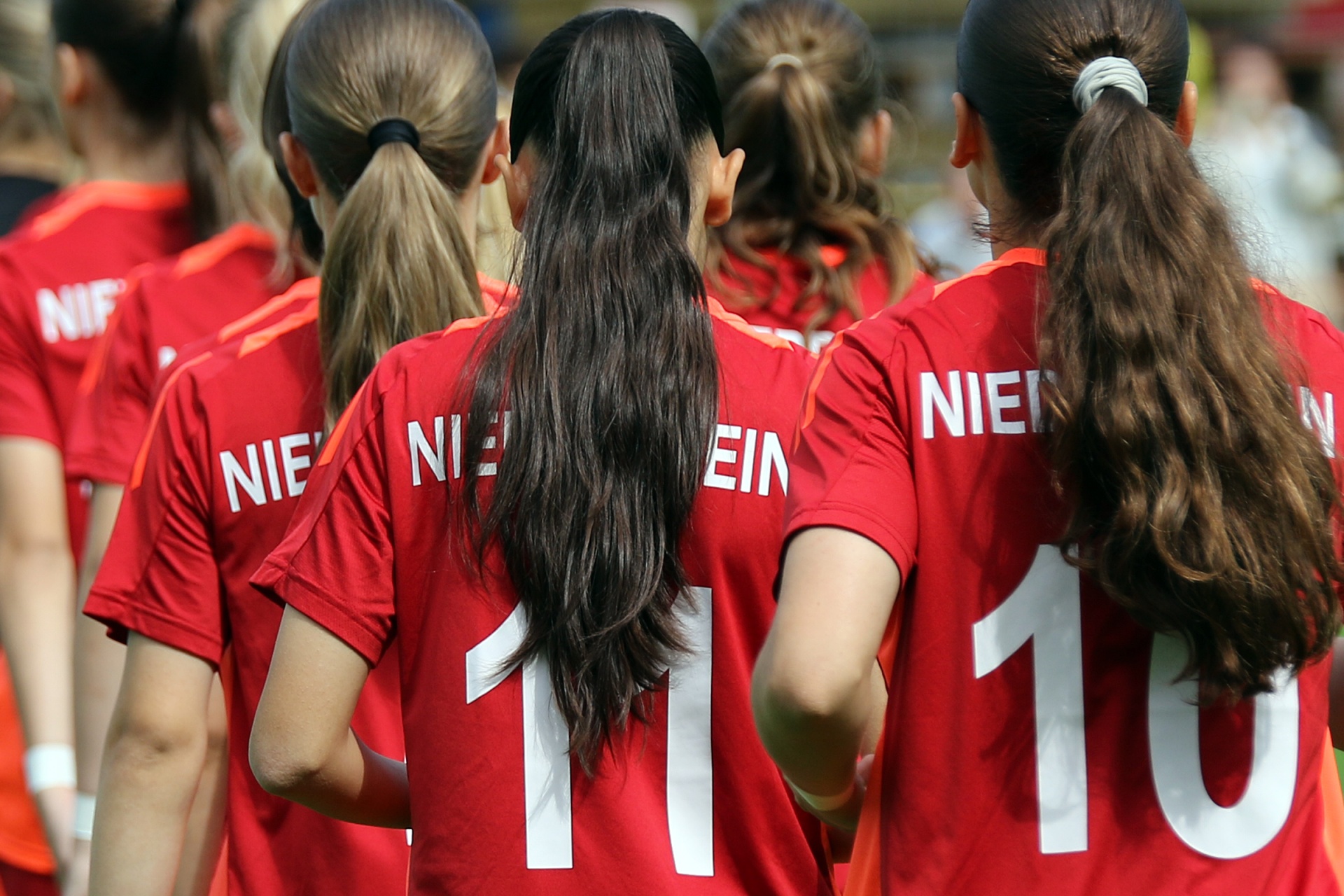 [{"clang_id":1,"value":"Fußballspielerinnen im roten Trikot mit Nummern auf dem Rücken, stehend, aus Rückansicht. Nummern 10 und 11 sind erkennbar."}]