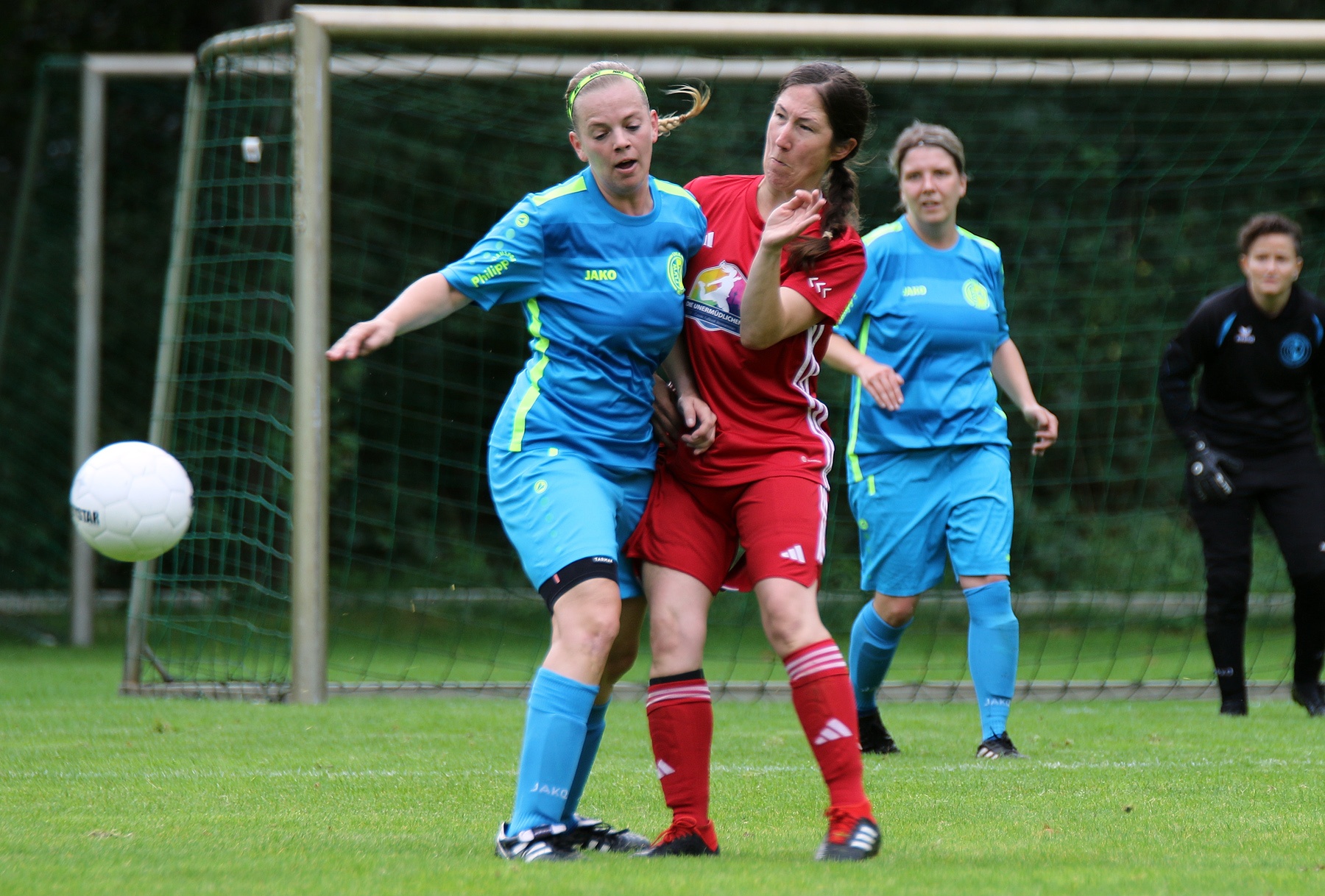 [{"clang_id":1,"value":"Fußballspiel: Zwei Spielerinnen kämpfen um den Ball. Eine trägt blaues Trikot, die andere rotes. Im Hintergrund weitere Spielerinnen und ein Fußballfeld."}]