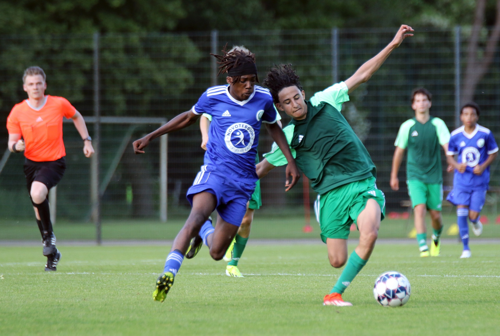 [{"clang_id":1,"value":"Zwei Fußballspieler kämpfen um den Ball auf einem grünen Rasen. Im Hintergrund weitere Spieler und ein Schiedsrichter."}]
