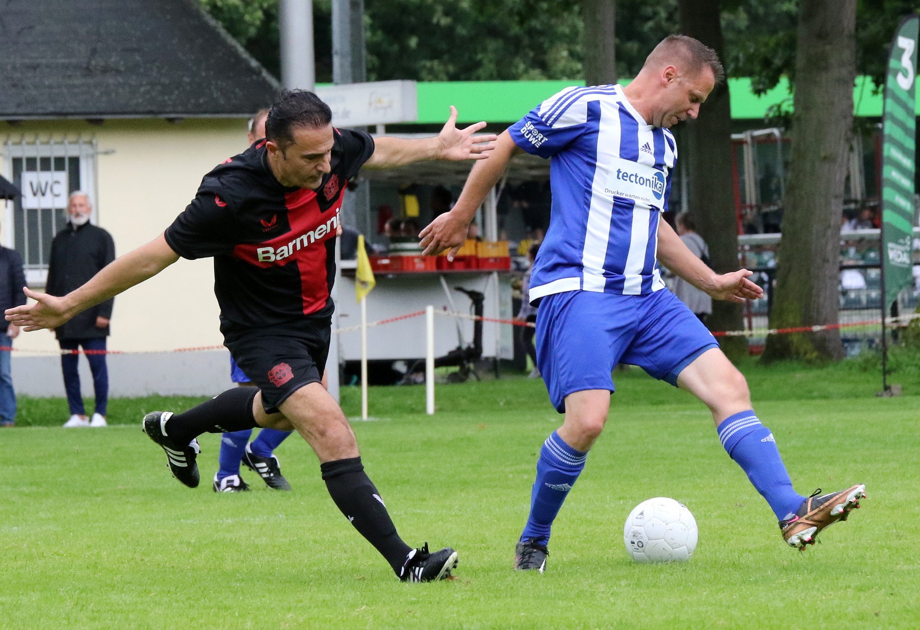 [{"clang_id":1,"value":"Zwei Fußballspieler auf grünem Rasen im Spiel. Links rotes Trikot mit \"Barmen\", rechts blau-weiß gestreiftes Trikot. Beide stoßen mit dem Fuß gegen den Ball."}]