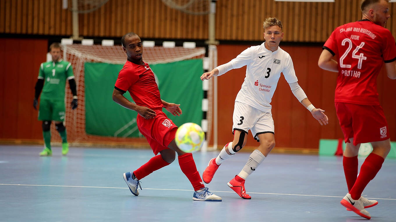 [{"clang_id":1,"value":"Futsalspiel: Zwei Spieler in Rot und Weiß kämpfen um den Ball auf blauem Hallenboden. Im Hintergrund weitere Spieler und eine grüne Wand."}]
