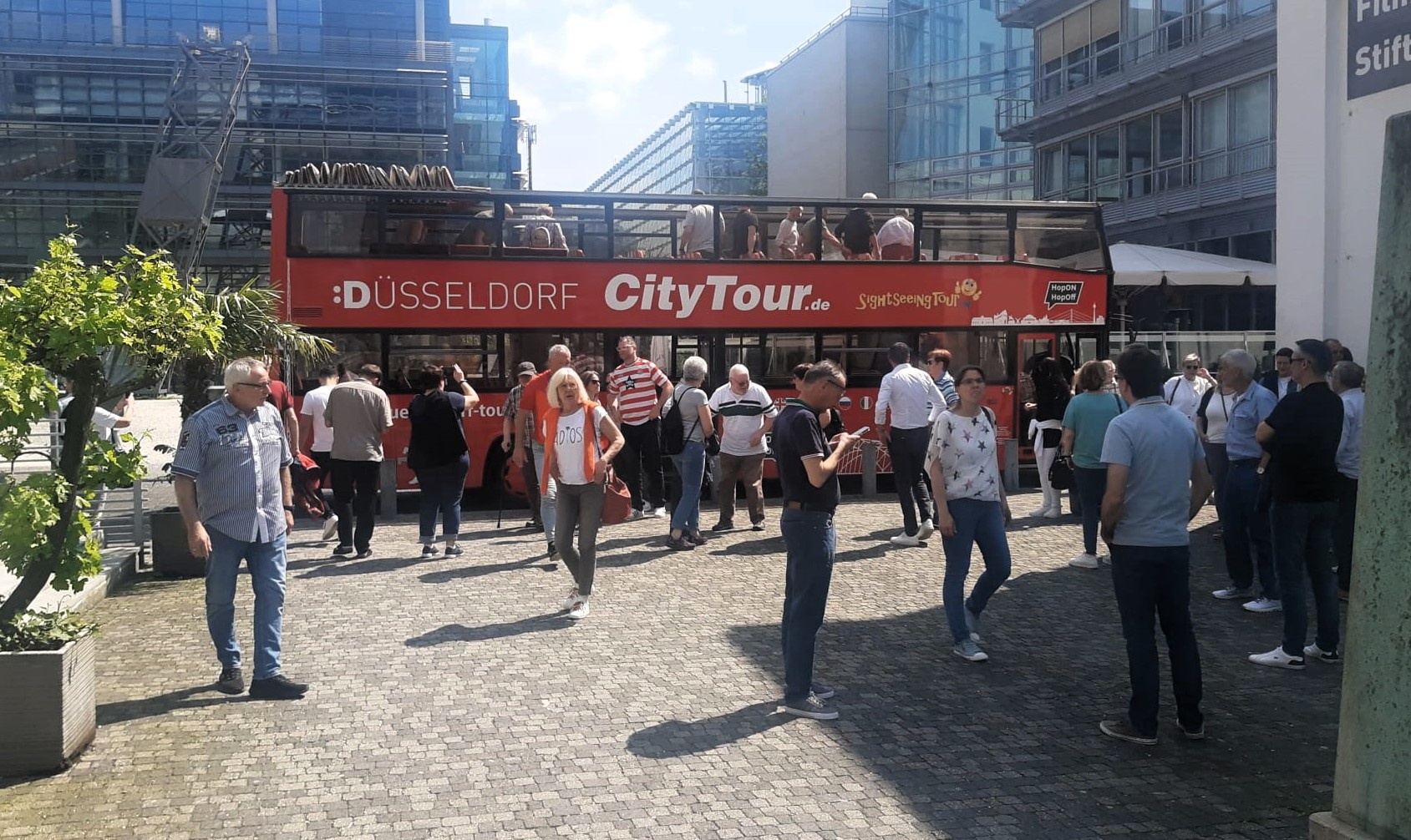 [{"clang_id":1,"value":"Touristenbus \"Düsseldorf CityTour\" steht an modernem Platz mit vielen Menschen. Gebäude im Hintergrund."}]