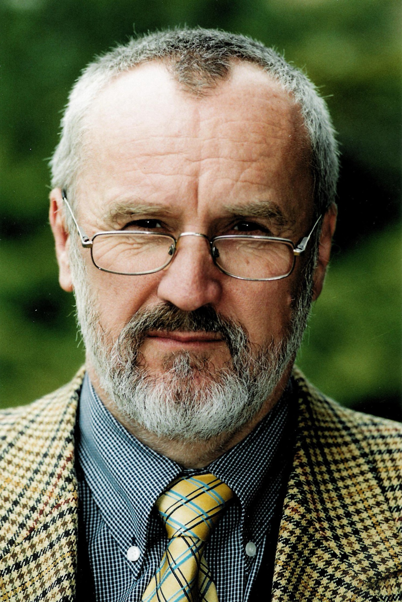 [{"clang_id":1,"value":"Mann mit Bart und Brille, trägt karierte Jacke und Krawatte. Blickrichtung frontal. Grüner Hintergrund unscharf."}]