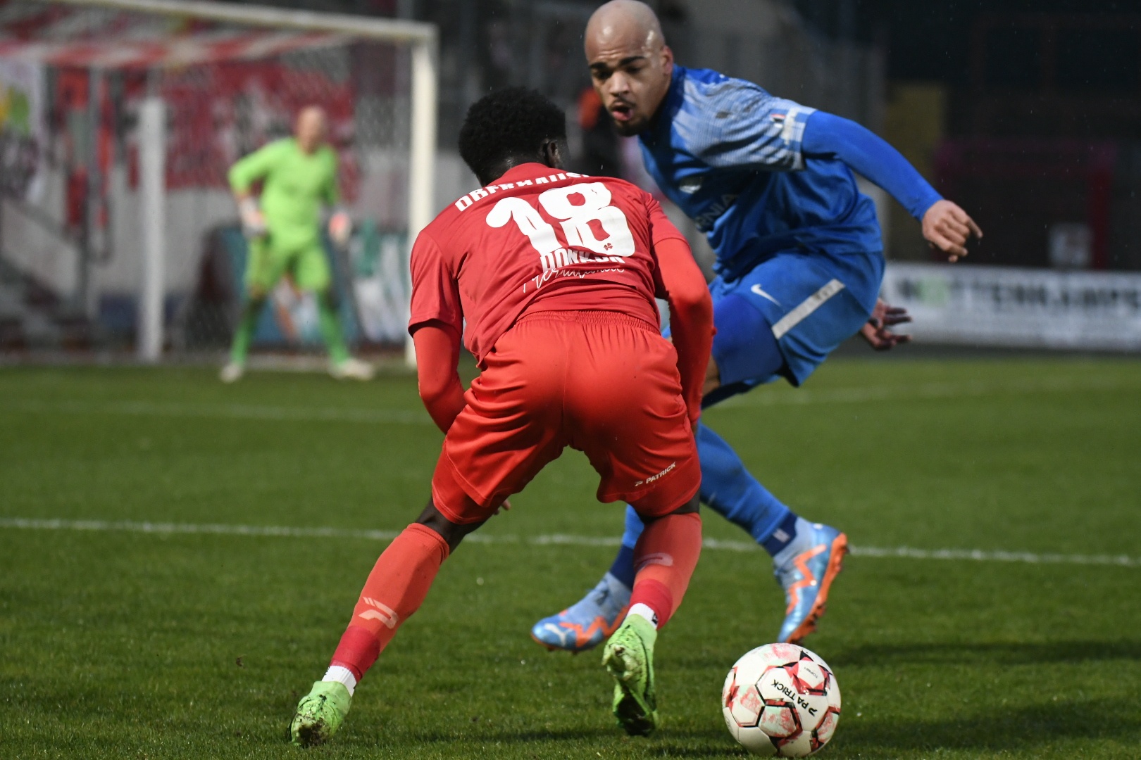 [{"clang_id":1,"value":"Zwei Fußballspieler kämpfen um den Ball auf dem Rasen. Im Hintergrund der Torwart und weitere Spieler."}]